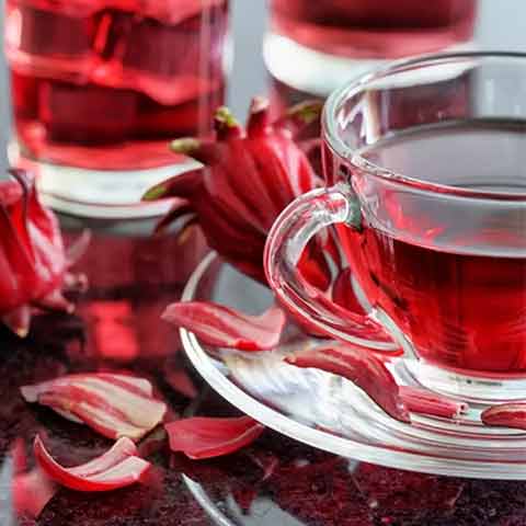 چای ترش برای سلامتی چای ترش دم شده در لیوان شیشه ای و گل های خشک چای ترش